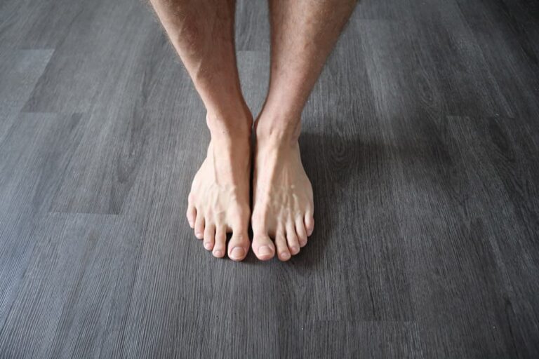 Visible veins on the feet and lower legs of a lean adult standing on a floor